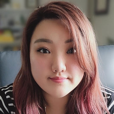 A person with light skin and red and pink hair wearing a black and white pattern shirt