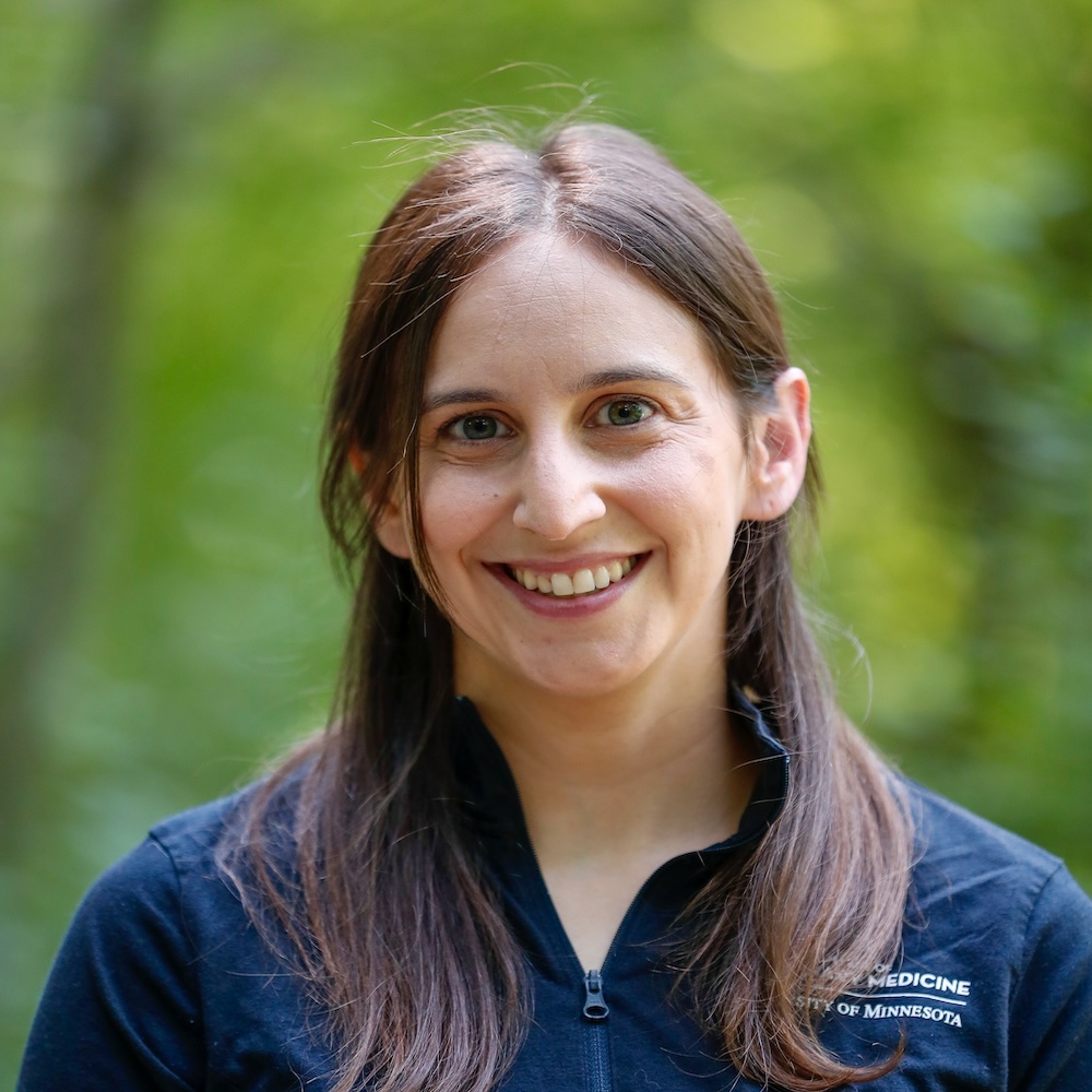 A person with fair skin and brown hair wearing a dark quarter-zip jacket